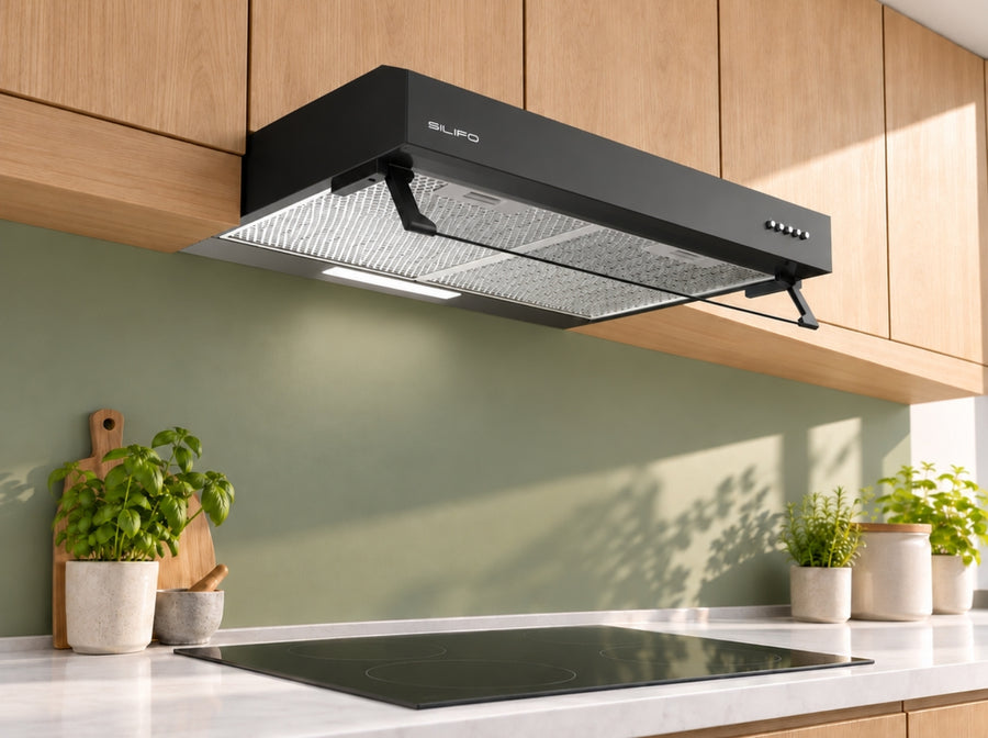 Black SILIFO SF6682 cooker hood above a ceramic hob in a kitchen with wooden cabinets and plants, angled view.